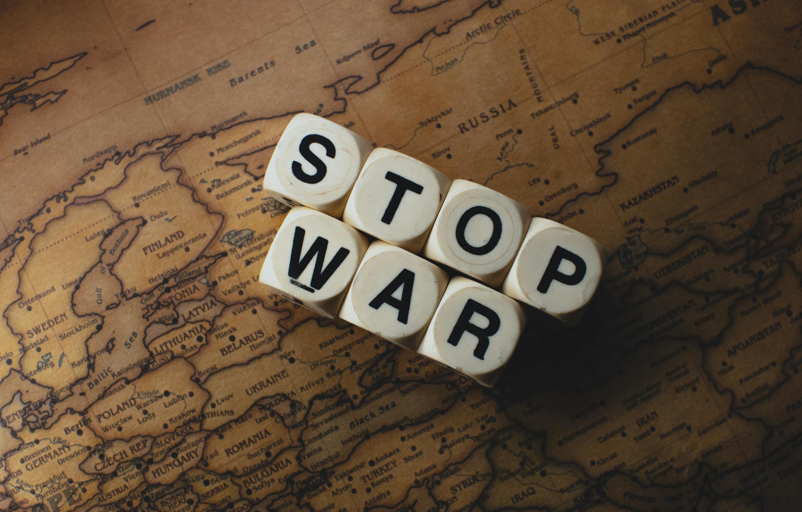 Dice with 'STOP WAR' on a vintage world map signifies peace.