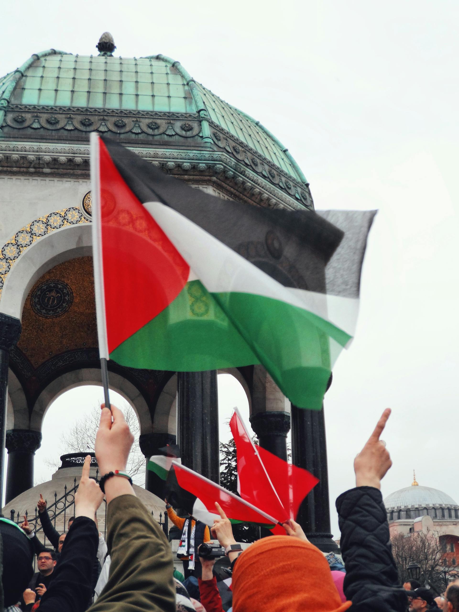 Protesters hold Palestine flags near historical monument in Istanbul, Turkey.