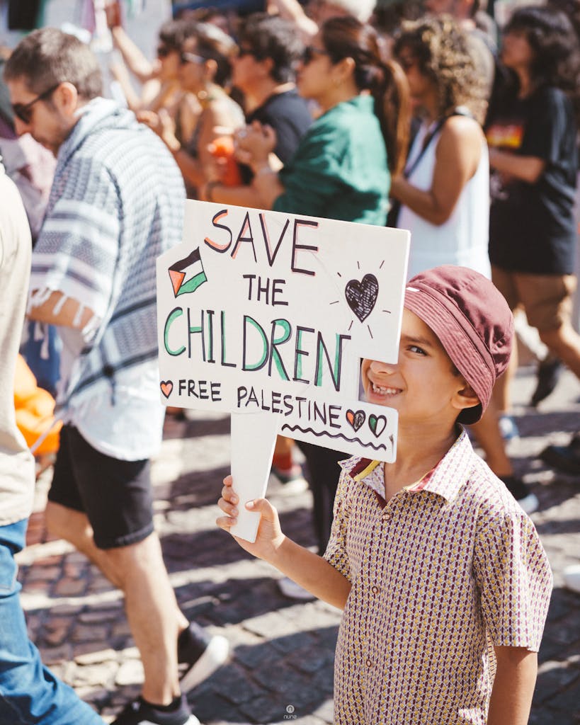A child at a protest rally holding a sign advocating for Palestinian children's rights.